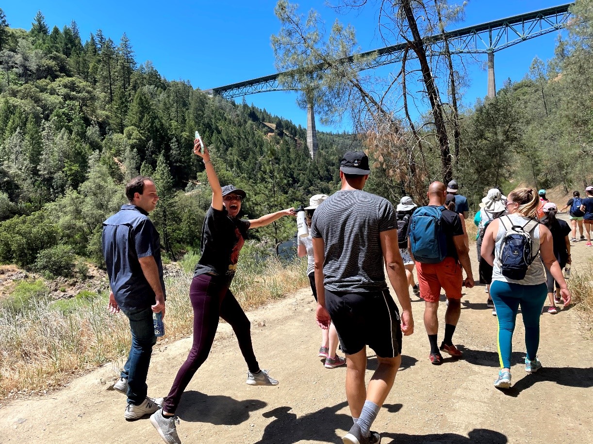 Residents walk down outdoor trail with railroad bridge above head.